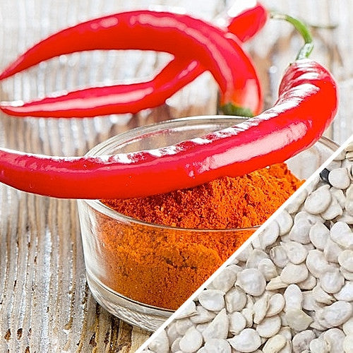 Red cayenne peppers with red chili powder and white seeds on wooden surface